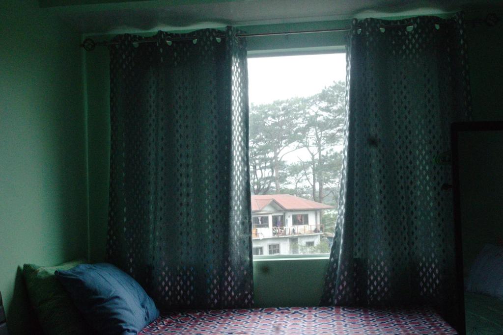 碧瑶Albergo Condotel - AB Pagadian Enterprise的一间卧室设有窗户,享有房子的景色