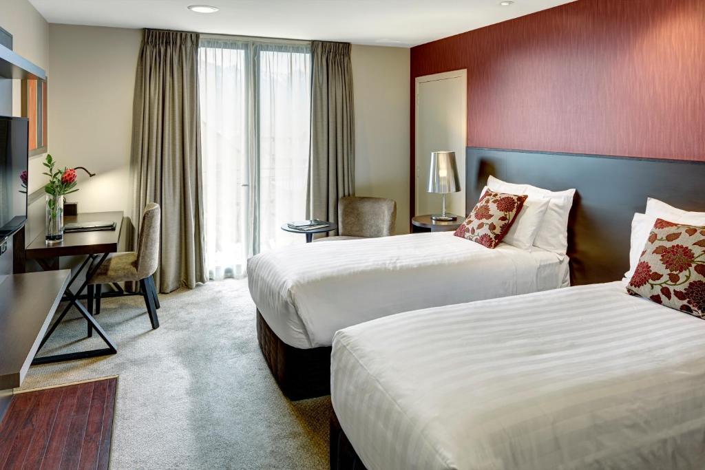 皇后镇Rendezvous Heritage Hotel Queenstown的有两张床和一张书桌的酒店房间