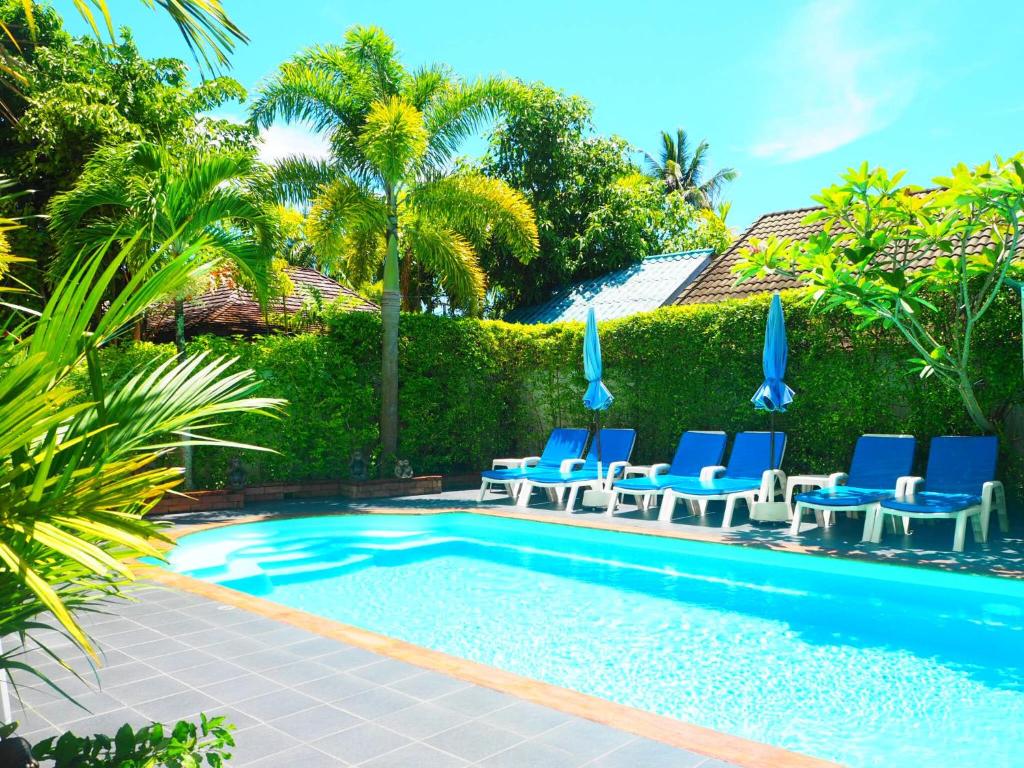 邦涛海滩Baan Rosa Bangtao Beach的一个带蓝色椅子的游泳池,棕榈树