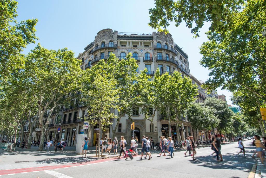 巴塞罗那Safestay Barcelona Passeig de Gràcia的人穿过大楼前的街道