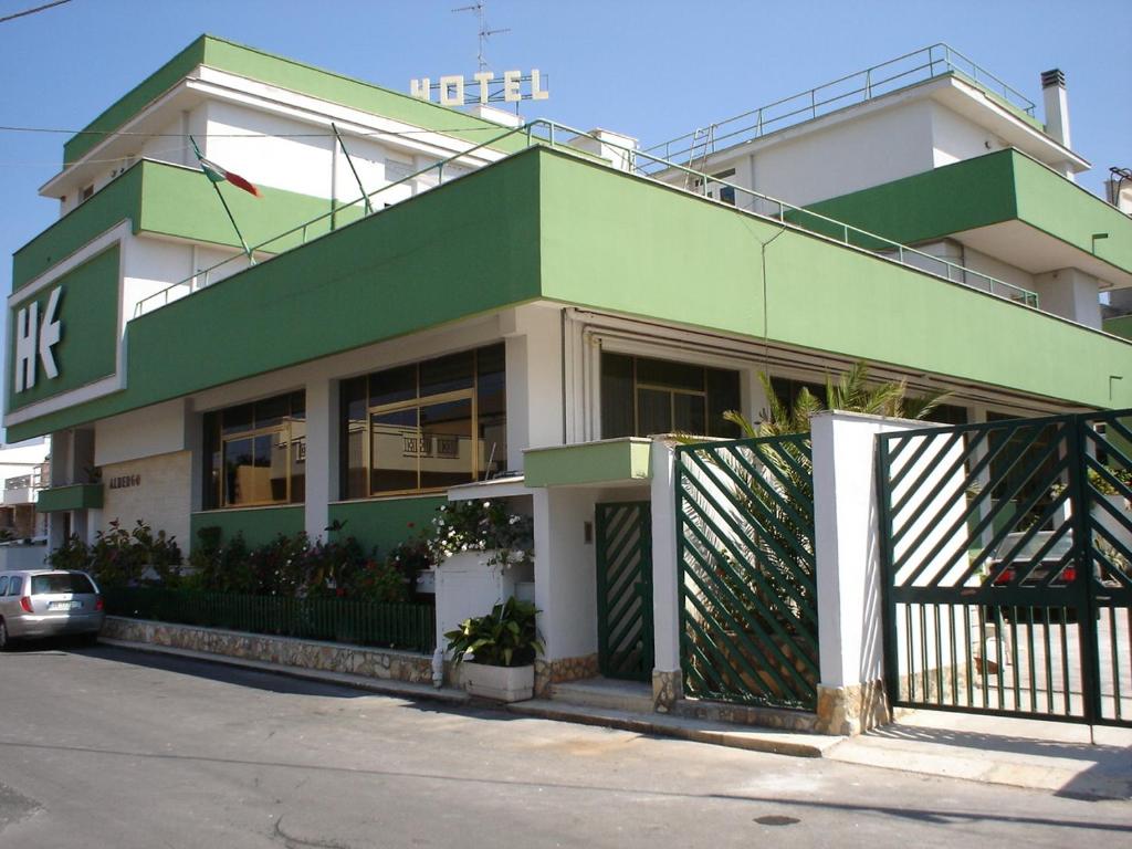 萨米凯莱-迪巴里艾斯贝里阿酒店的一座绿色的白色建筑,前面有停车位