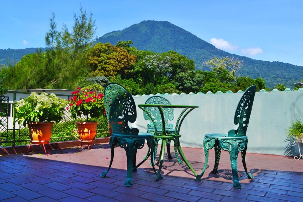 圣萨尔瓦多绿洲住宿加早餐旅馆的庭院里设有两把绿色椅子和一张桌子