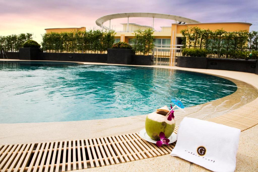 曼谷金色珍珠酒店（原金色珍珠公寓）的游泳池旁的长凳上的椰子