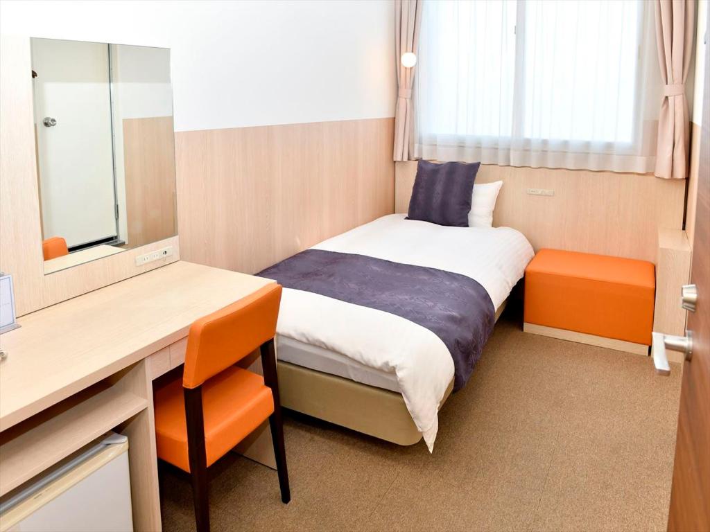 Neyagawa大阪寝屋川新指挥官酒店的小房间设有床、书桌和镜子