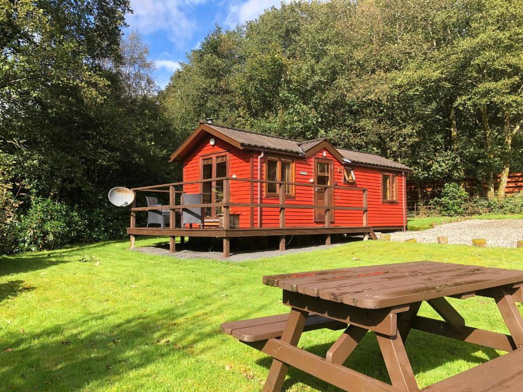 达农Rashfield Sheilings - Riverside Lodges, by Pucks Glen, Dunoon的一间红色小屋,前面设有野餐桌