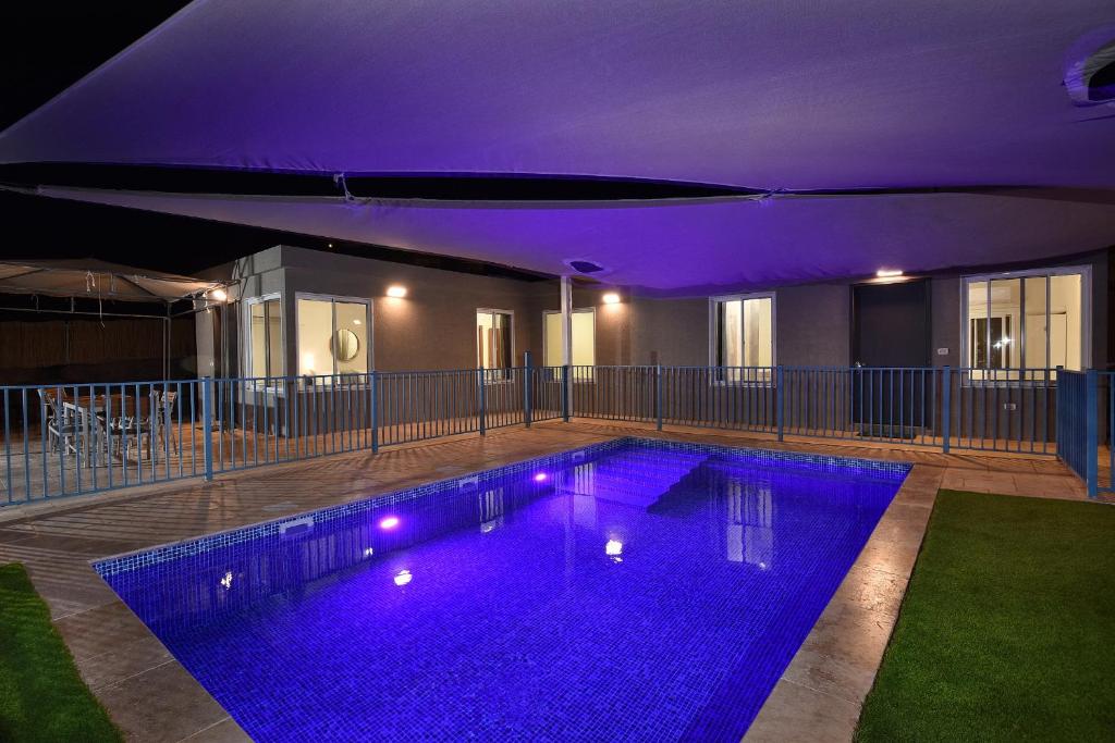 哈德内斯Shmulik's Resort的一座建筑中一座带紫色灯光的游泳池
