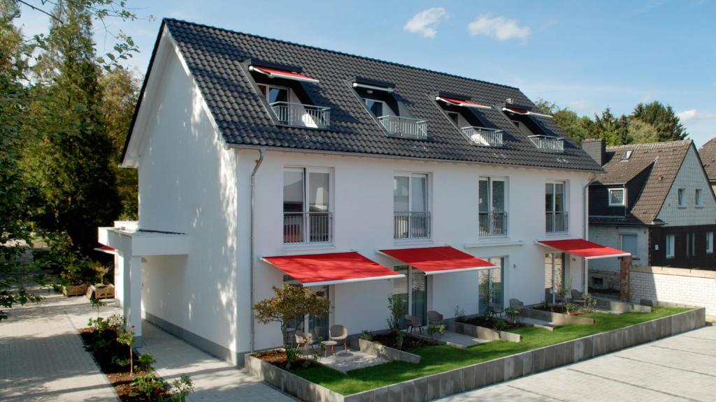 贝尔吉施格拉德巴赫Hotel Boskamp的白色房子,有红色屋顶和植物