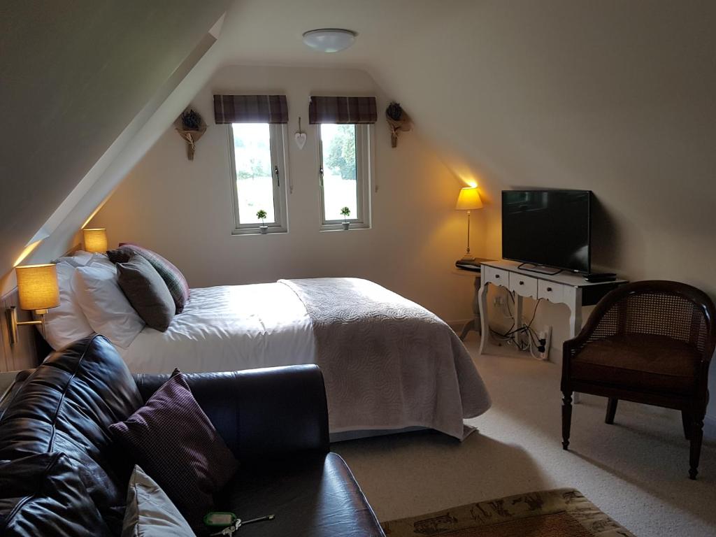 塔博雷The Barn Tarporley的一间卧室配有一张床、一张沙发和一台电视