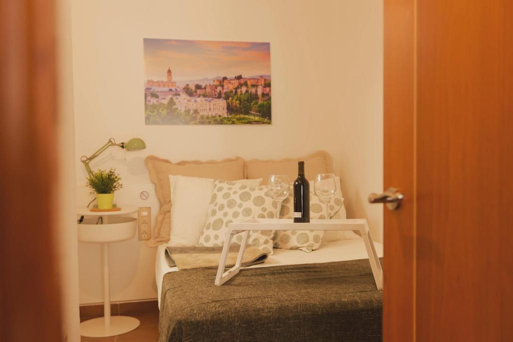 马拉加Estancia de Invitados de Casa Tais的一间卧室配有一张床和一张桌子及一瓶葡萄酒