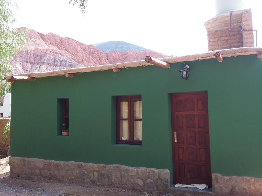 普尔马马尔卡Hospedaje Doña Velia的绿色房子,设有2扇窗户和1扇门