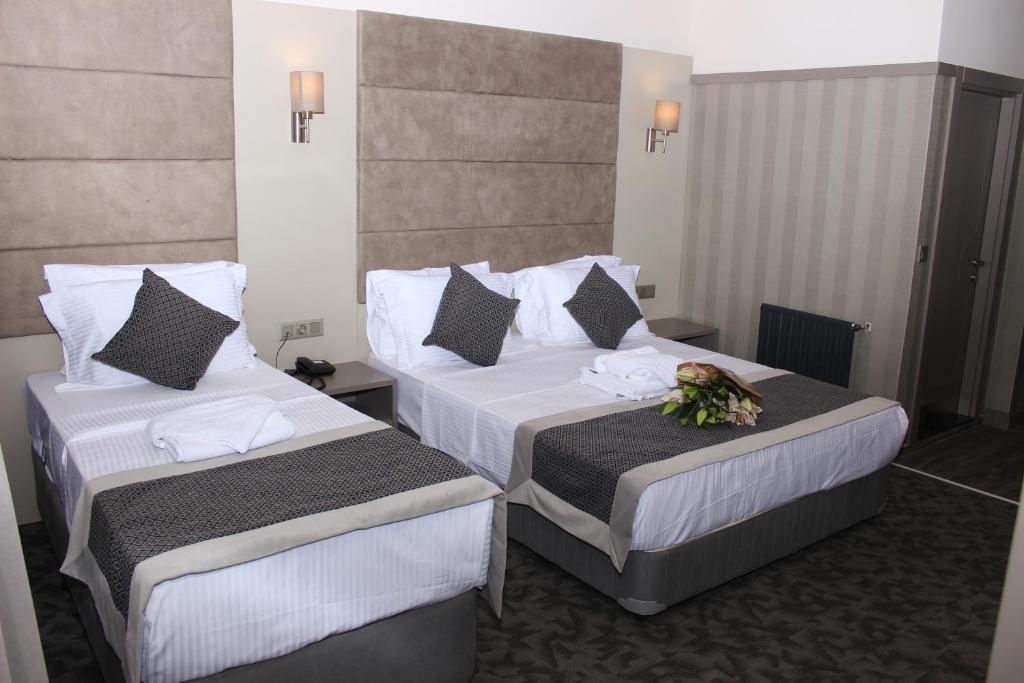 伊斯坦布尔Anka Premium Hotel的两张位于酒店客房的床,上面有鲜花