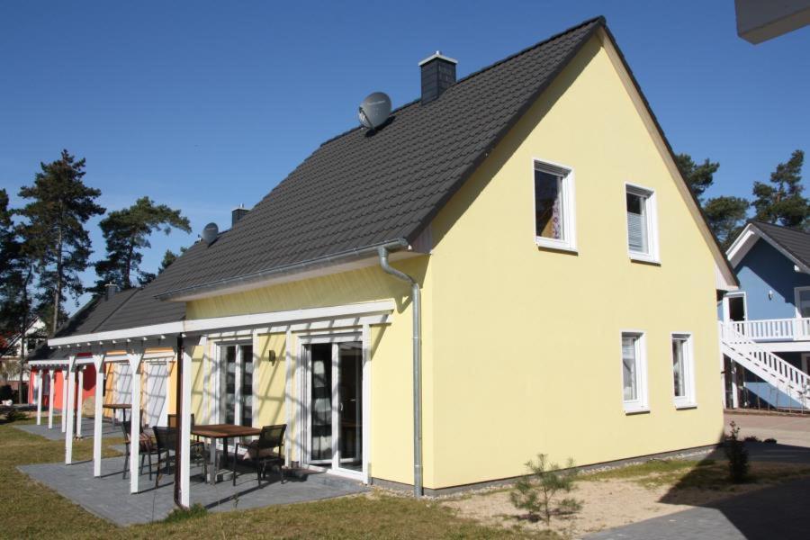 勒伯尔K 97 - stilvolles Ferienhaus mit Kamin & WLAN am See in Röbel an der Müritz的黄色的房子,有黑色的屋顶和一张桌子