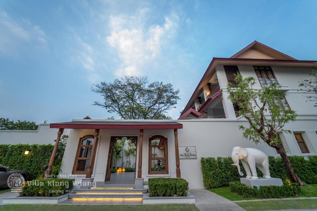 清迈Villa Klang Wiang的前面有大象雕像的白色房子