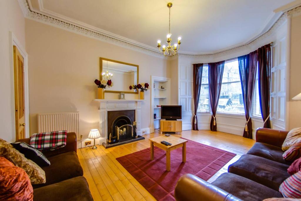 爱丁堡JOIVY Modern 3 bed flat, closeby the Meadows & Old Town的带沙发和壁炉的客厅