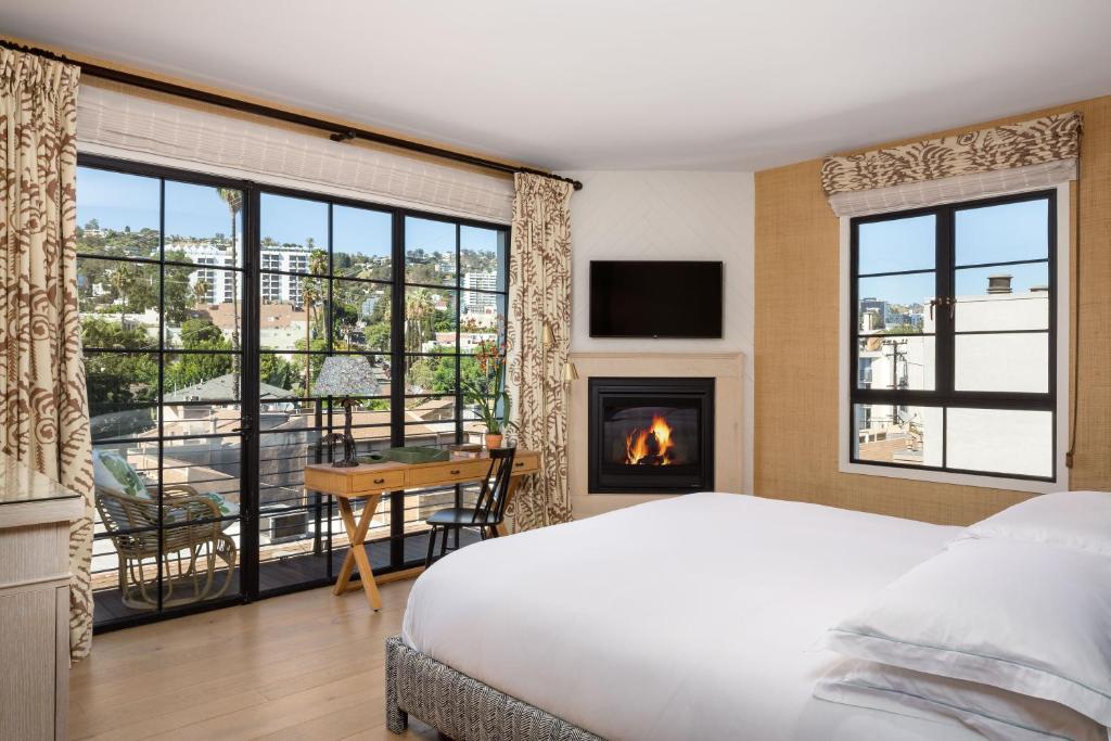 洛杉矶Hotel 850 SVB, West Hollywood, a Member of Design Hotels的一间卧室配有一张床、一个壁炉和一张书桌