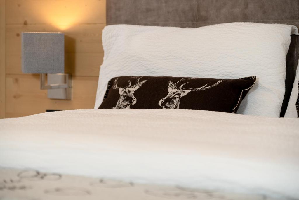 普雷达佐GARNI' Margherita的一张带黑色枕头的白色床,上面有鹿