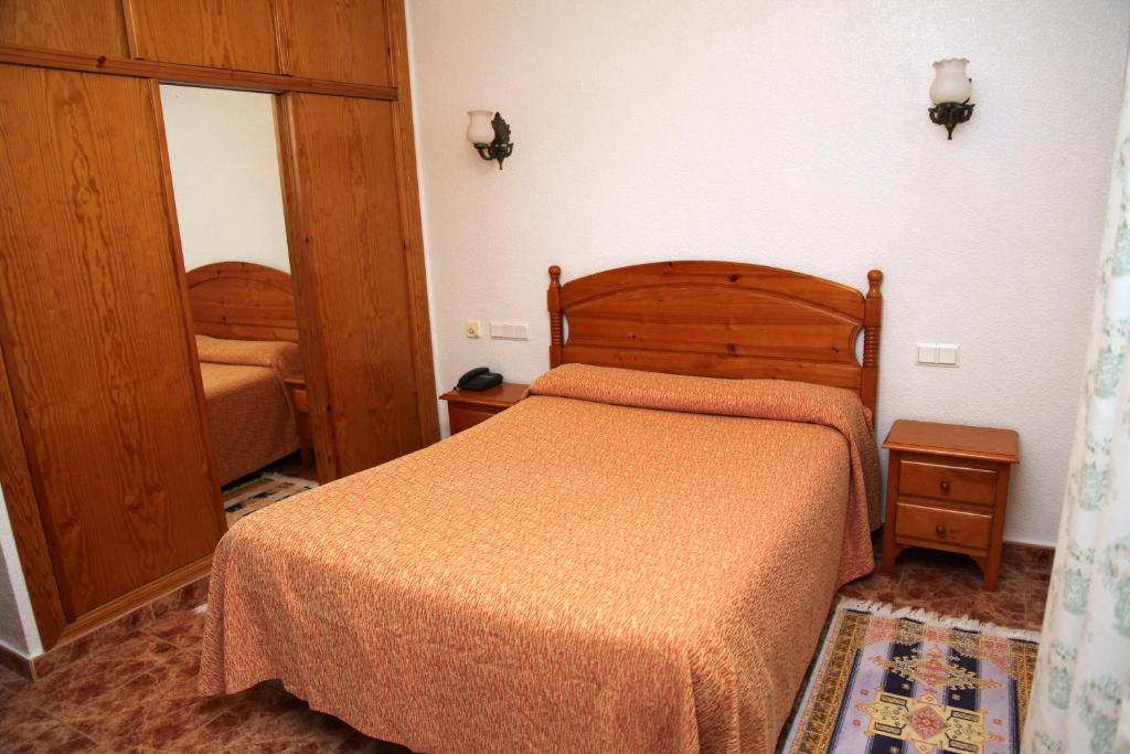 El AlquiánHotel Los Arcos的一间卧室配有一张带木制床头板的床