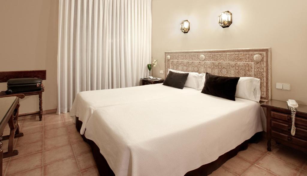 托莱多加利亚纳公主酒店的卧室配有一张带白色床单和枕头的大床。