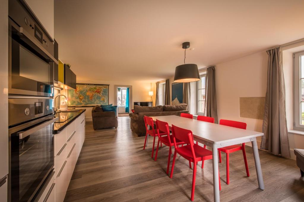 因特拉肯Dependance Penthouse的厨房以及带桌子和红色椅子的客厅。