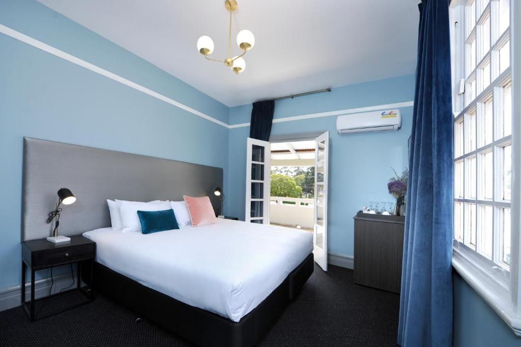 珀斯斯特林阿姆斯酒店的卧室配有白色的床、蓝色的墙壁和窗户。