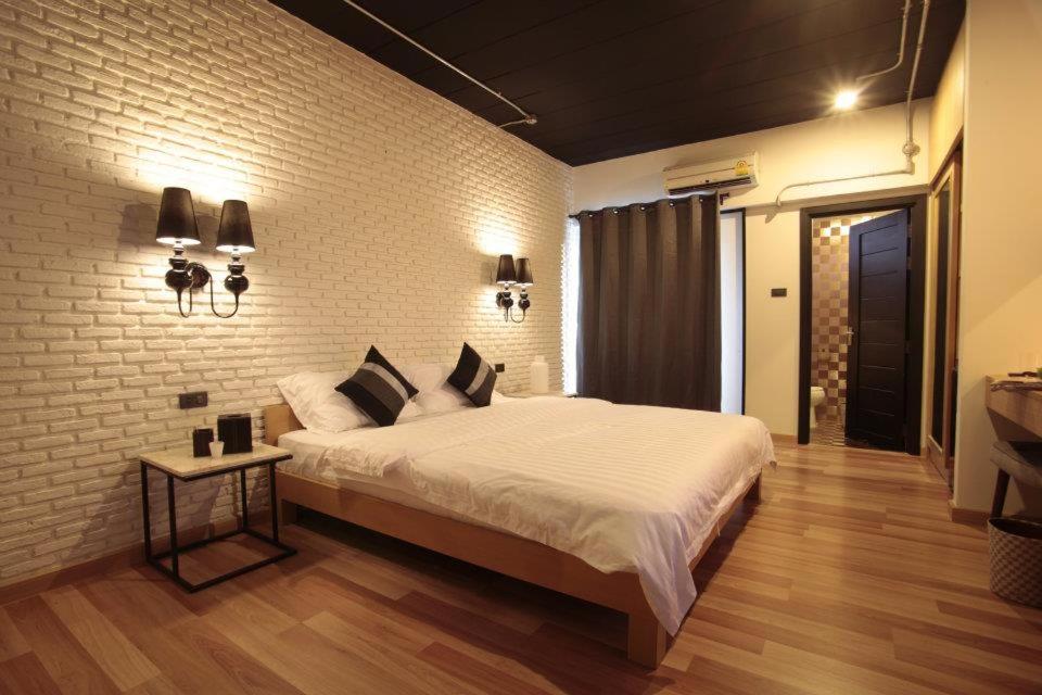 佛统Diary Suite的一间卧室设有一张大床和砖墙