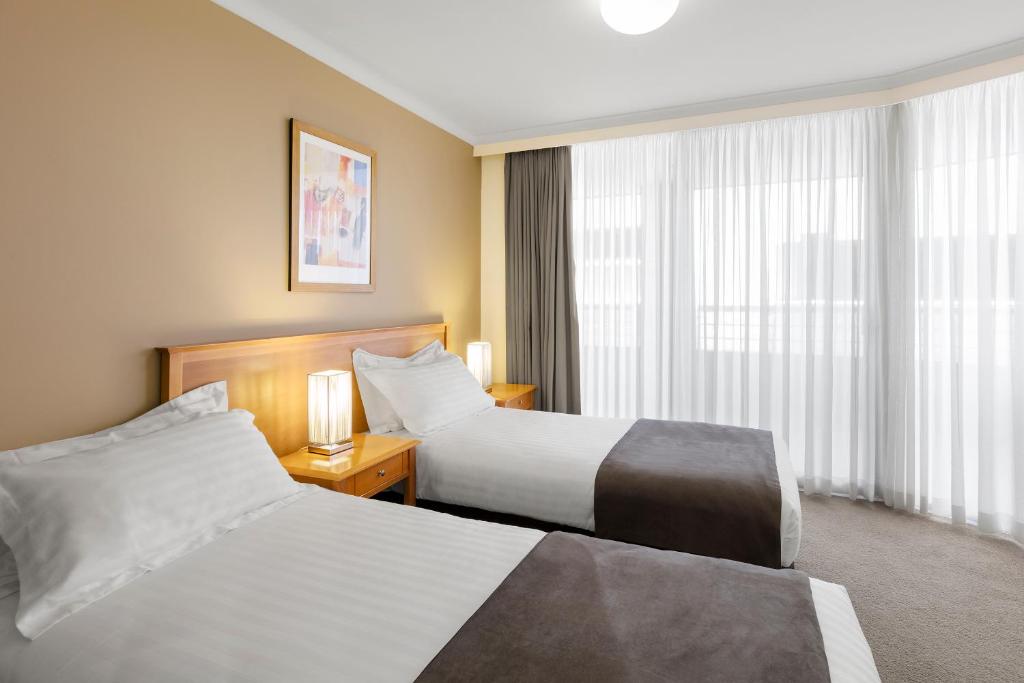 堪培拉Nesuto Canberra的酒店客房设有两张床和窗户。