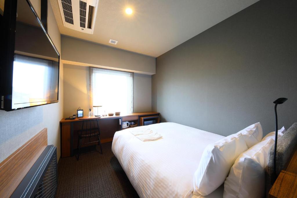 东京ICI HOTEL Ueno Shin Okachimachi的一间卧室配有一张床、一张书桌和一个窗户。