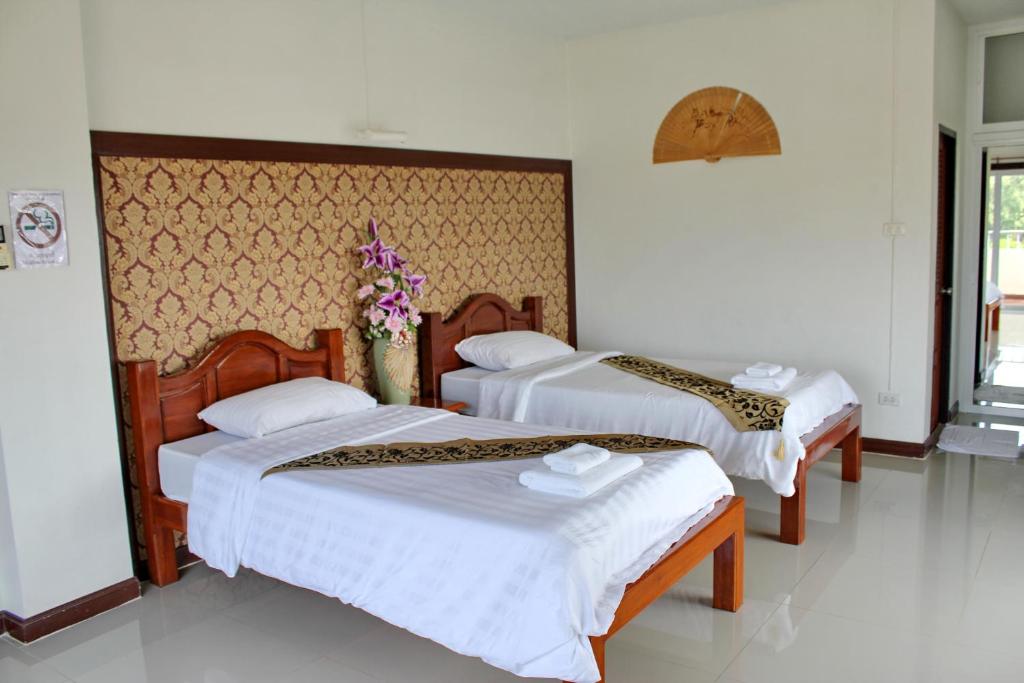 清迈Mantra Place的一间卧室配有两张带白色床单和鲜花的床。