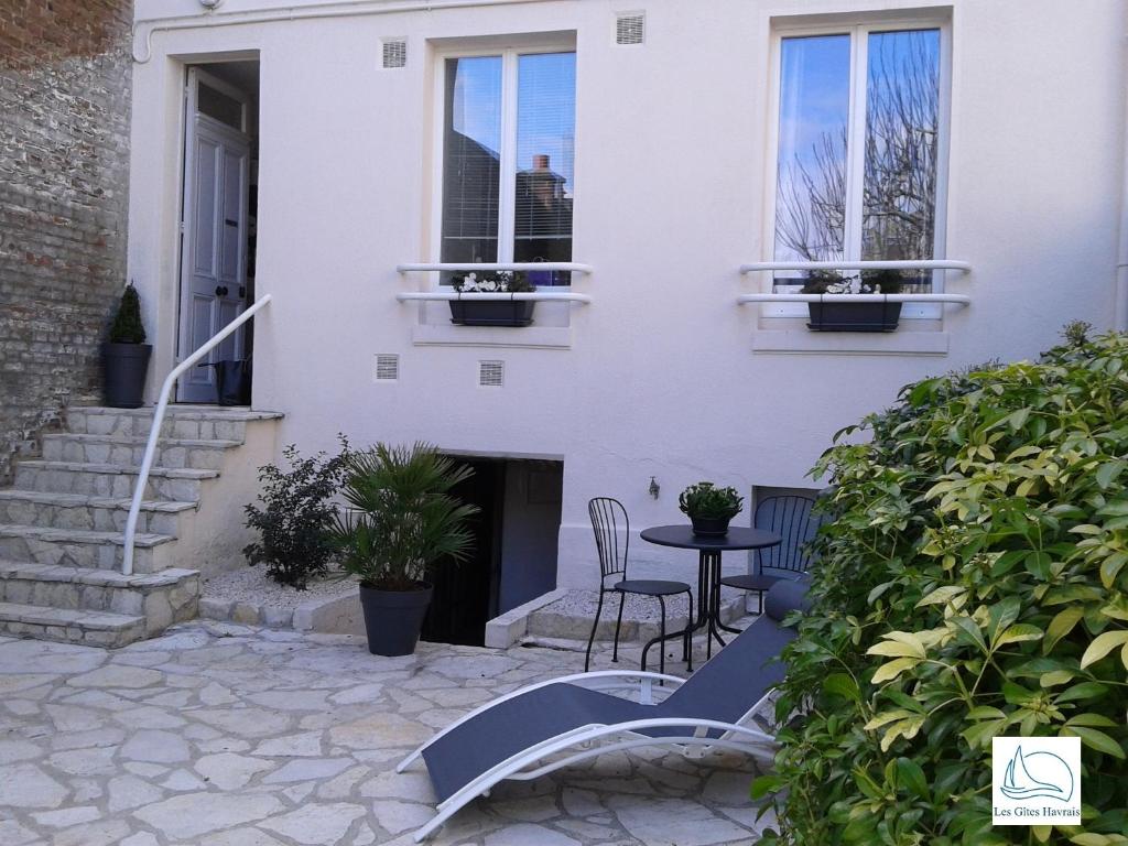 勒阿弗尔Les Gîtes Havrais的庭院内带桌椅的白色房屋