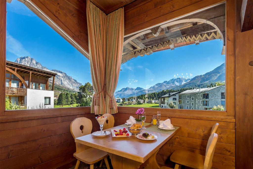 马洛亚施瓦泽豪斯瑞士优质酒店的一间带桌子和大窗户的用餐室