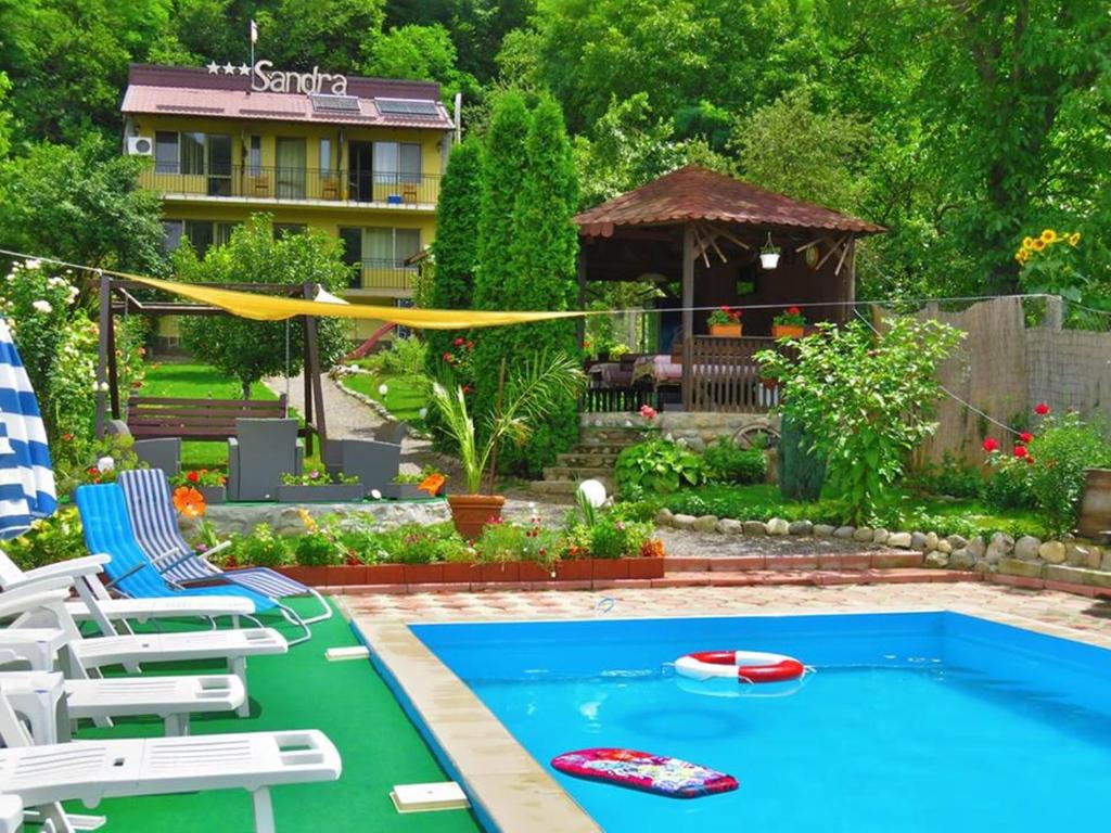 伯伊莱海尔库拉内Cazare Casa Sandra的后院设有带椅子和充气木筏的游泳池