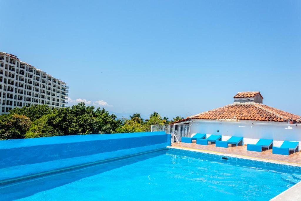 巴亚尔塔港Hotel Encino Malecón Centro Puerto Vallarta的一座带蓝色椅子的游泳池和一座建筑