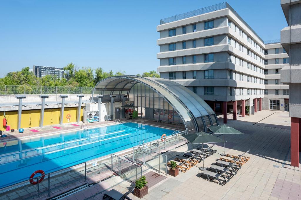 马德里Madrid Airport Suites, Affiliated by Meliá的大楼前的游泳池