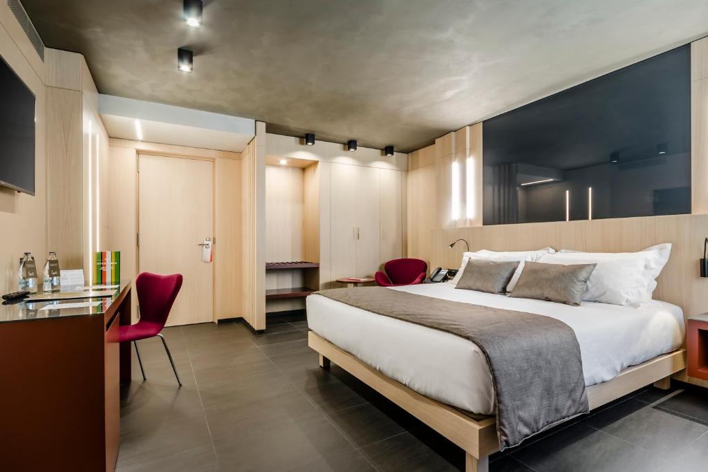 安道尔城大都会酒店的一间卧室配有一张大床和红色椅子