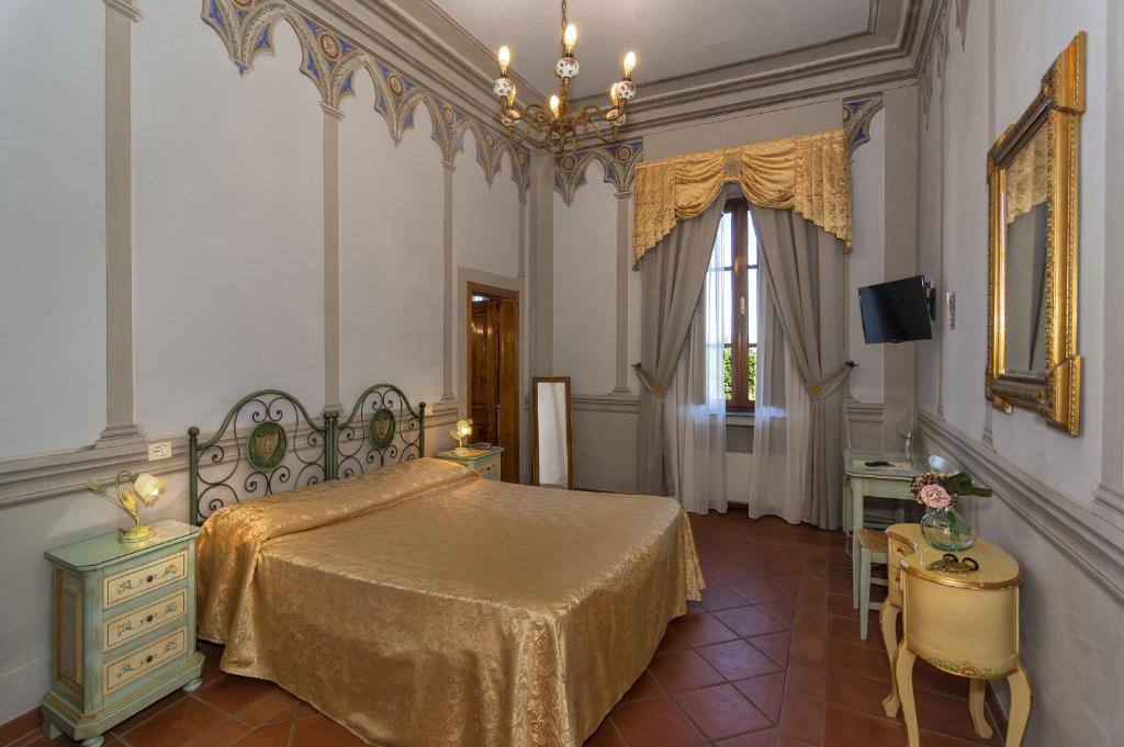 卢卡彻利别墅酒店的一间卧室配有一张床、一张桌子和一个窗户。