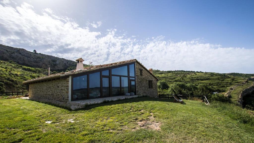 Villarroya de los PinaresMasía el Cabrero的山丘上带玻璃窗的石头房子
