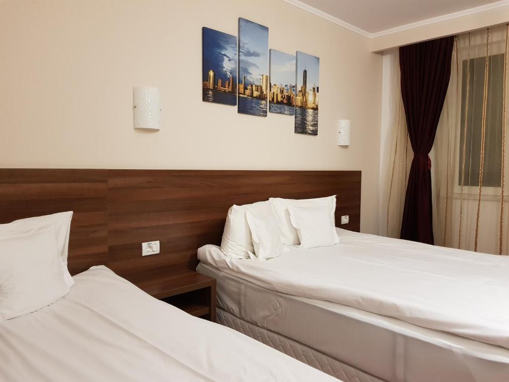 阿尔巴尤利亚赫耳墨斯酒店的配有白色床单的酒店客房内的两张床