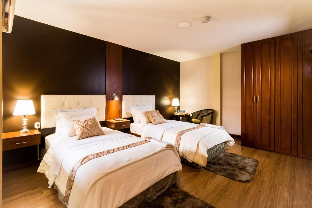 昆卡Hotel Boutique Castilla de Léon的酒店客房设有两张床和两盏灯。