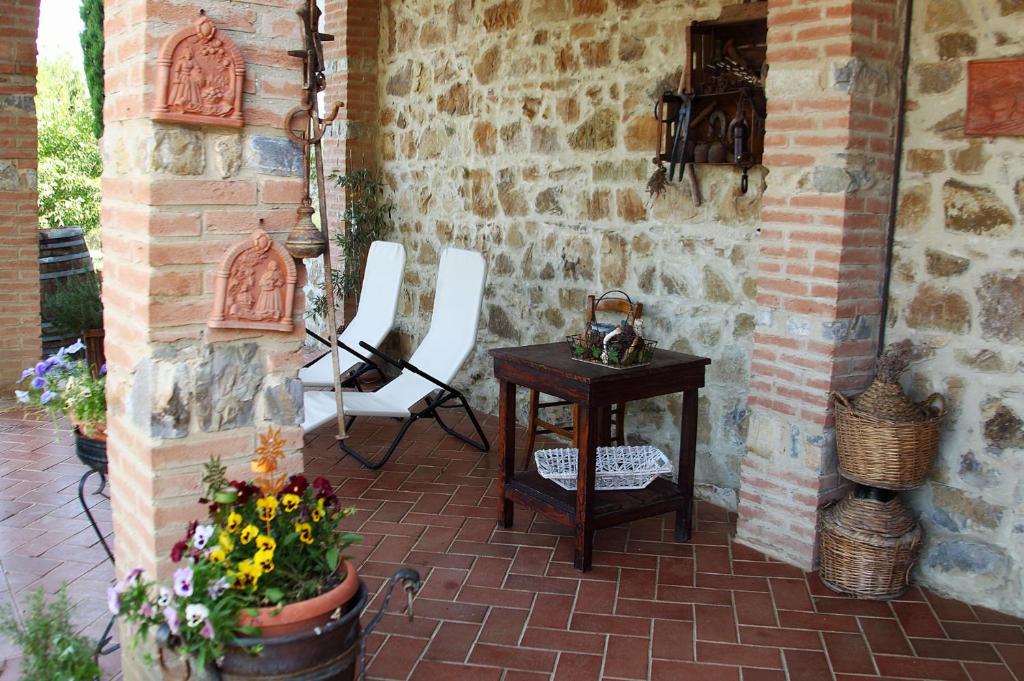 塞吉阿诺席尔瓦农家乐的庭院设有桌子、白色椅子和砖墙