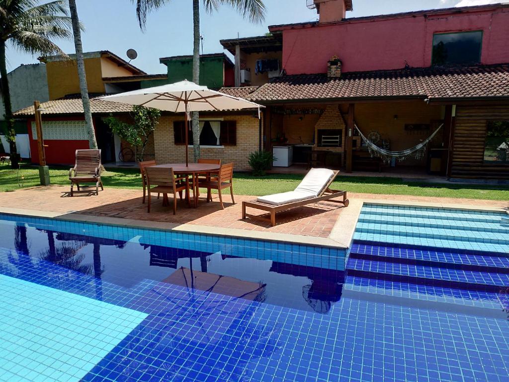 伊利亚贝拉Suíte Água Branca Residencial Exclusive的一个带桌椅的游泳池和一个房子