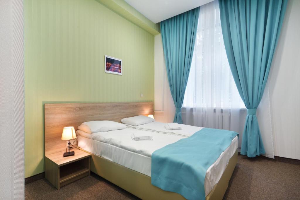莫斯科City Star的一间卧室配有床和蓝色窗帘的窗户