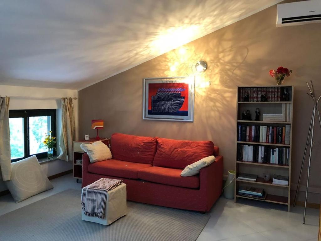 伊夫雷亚La mansarda di Orni的客厅配有红色沙发和书架