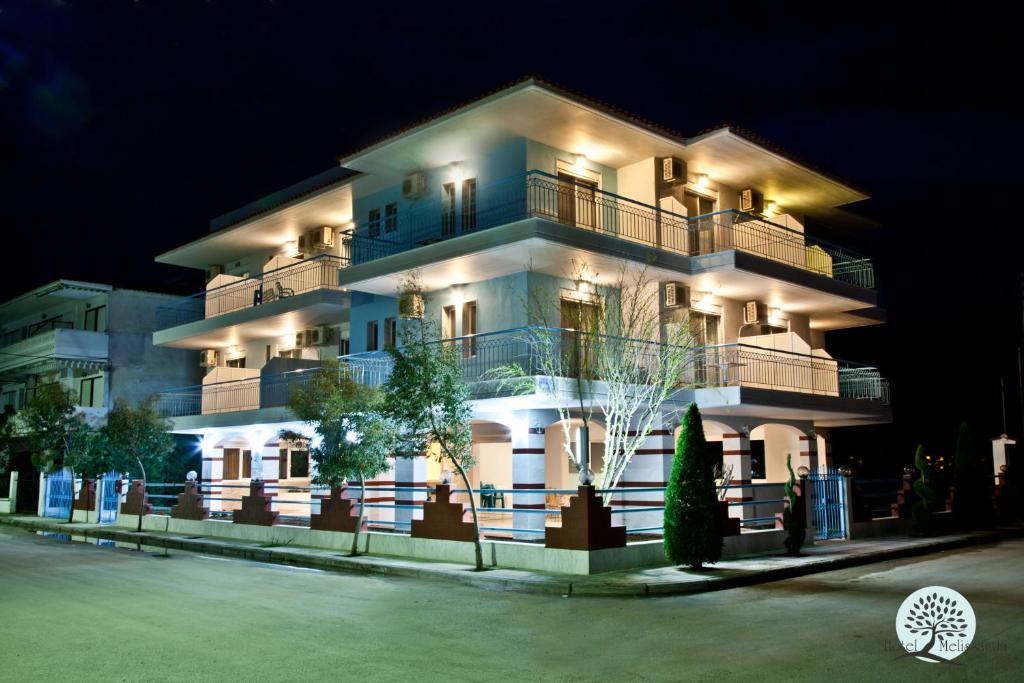 帕拉利亚狄奥尼索Hotel Melissanthi的一座白色的大建筑,晚上有灯