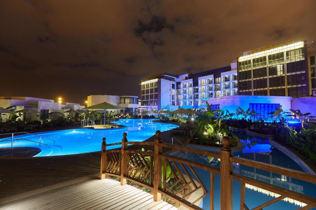 塞拉莱Millennium Resort Salalah的设有一个夜间大型游泳池的度假村