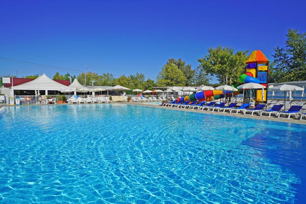 佩斯基耶拉德加达蝴蝶野营村旅馆的度假村的游泳池,配有椅子和遮阳伞
