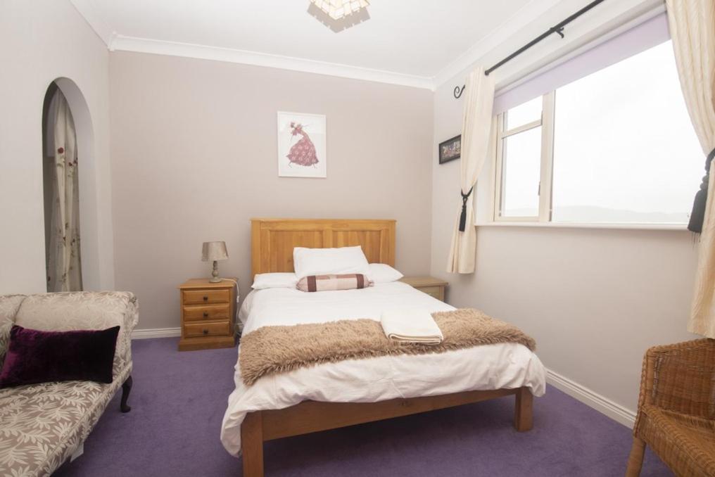 肯梅尔Poppyfield House, Kenmare的一间卧室设有一张床、一个窗口和一把椅子
