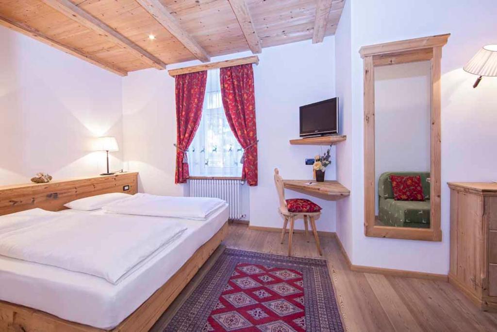 塞尔瓦迪加尔代纳山谷科洛那克朗酒店的一间卧室设有一张床、一个窗口和一把椅子