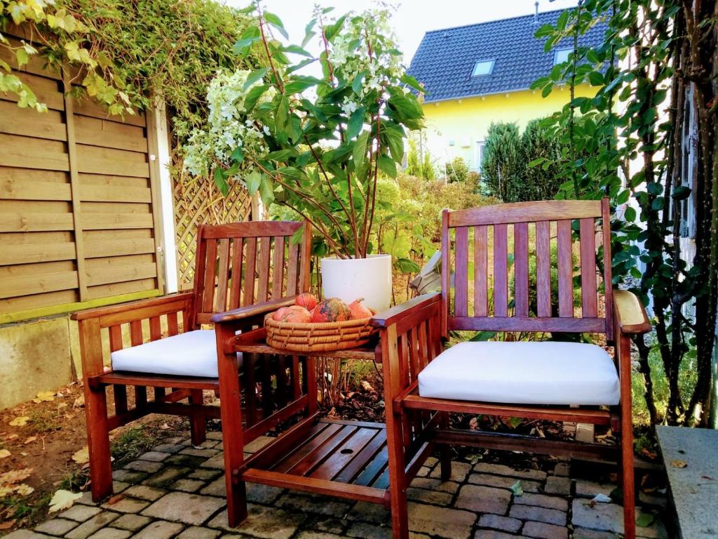 巴特菲尔伯尔Art & Nature Apartments in der Nähe FFM-Messe的两把木椅坐在庭院里,放着一篮水果