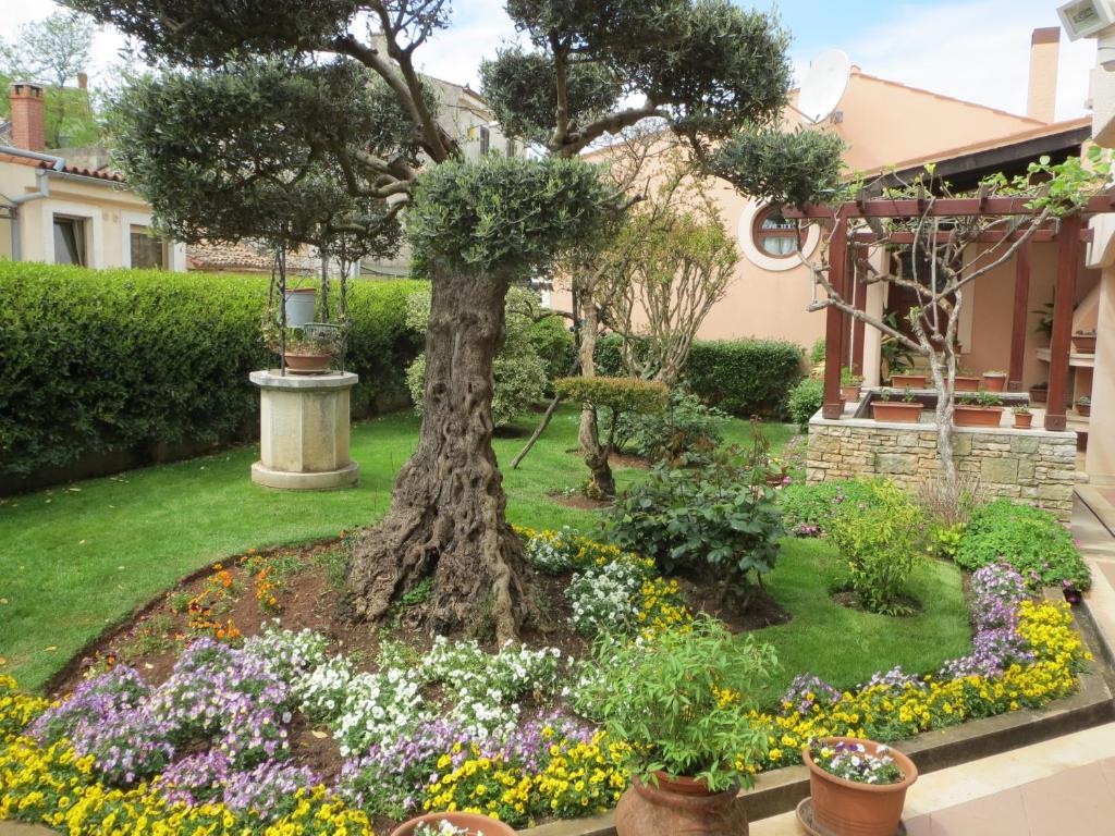 塔尔Apartments Mediteraneo的一座花园,在房子前面有树和鲜花