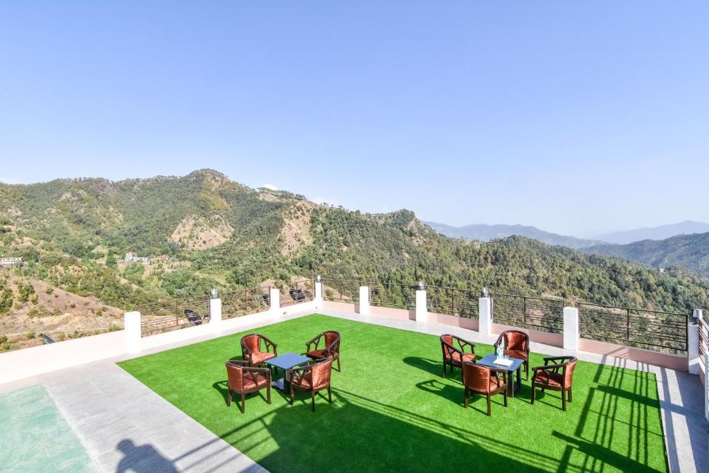 西姆拉Hotel Kaithli Hills Shimla的绿色草坪上带桌椅的庭院